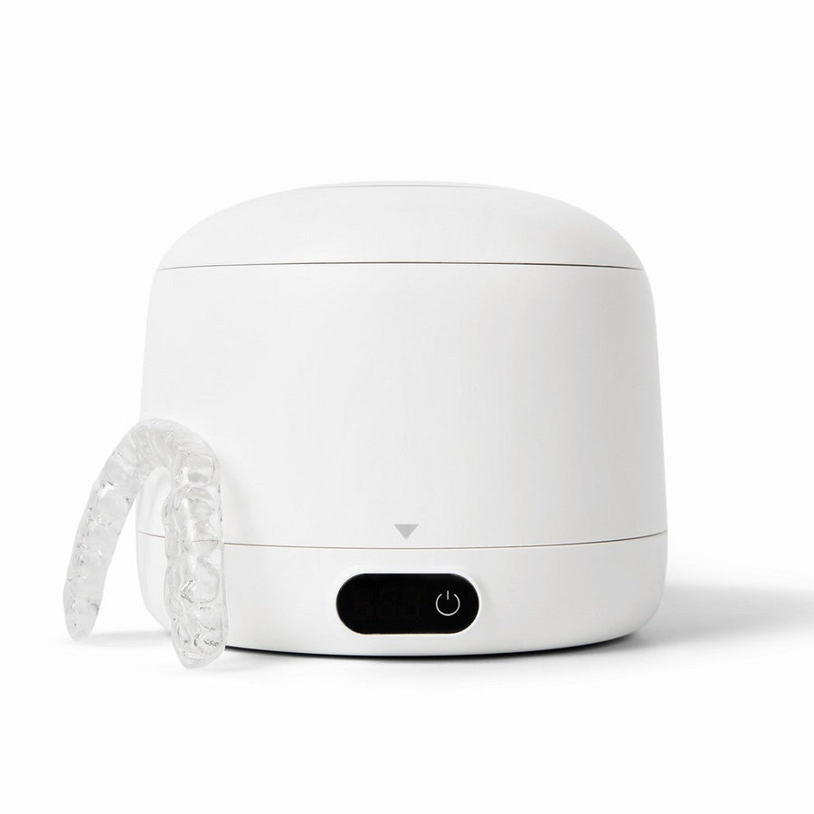 A white ultrasonic cleaner for retainers and night guards and a clean retainer.